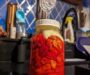 Glasburk med röda chilipeppar och jäsningslock i ett kök
