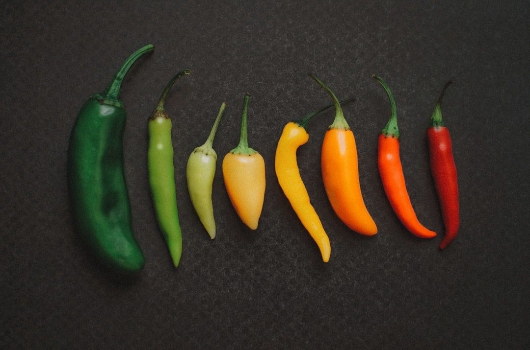 Åtta chilifrukter i färgskala från grönt till rött